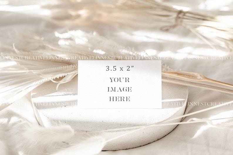 May include: A white card with the text "3.5 x 2" and "YOUR IMAGE HERE" on a white textured surface with white dried flowers.