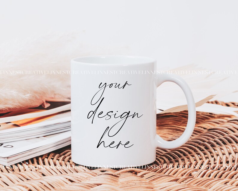 K&ouml;nnte beinhalten: Wei&szlig;e Keramiktasse mit einer schwarzen Aufschrift "your design here" auf einer geflochtenen Weidenoberfl&auml;che.