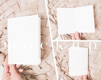 May include: Three blank white cards on a woven straw background. The cards are different sizes and are held by hands.
