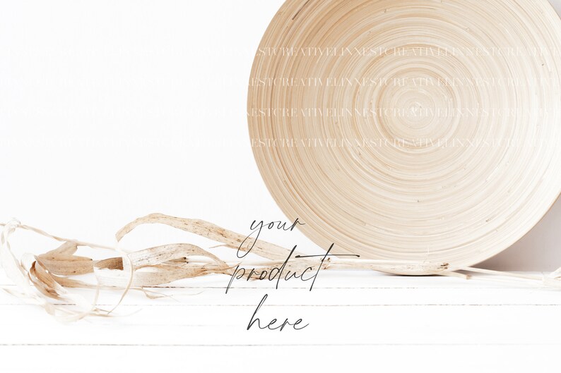 May include: A white wooden surface with a natural woven bowl and dried grass. The text "your product here" is written in black cursive.