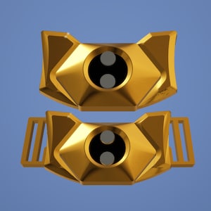 May include: Two gold-coloured metal watch bands with a geometric design. Each band has a circular cutout with two black circles inside.