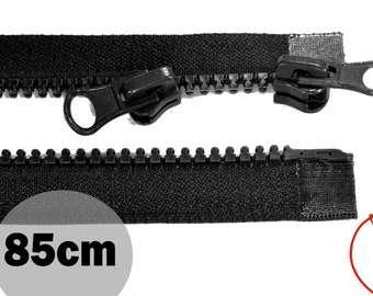May include: A black plastic separating zipper with two matching black sliders and pull tabs. The zipper tape is black fabric. A circular gray graphic overlay displays the text 85cm, indicating the length of the zipper component shown.