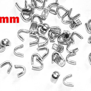 May include: A pile of silver metal 5mm cord ends. These are used for making jewellery or other crafts.