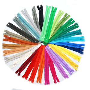 May include: A selection of zipper tapes in a range of colours arranged in a circle. Zipper tape is a common sewing supply used for clothing and other projects.