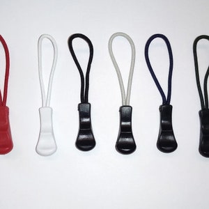 May include: Eight zipper pulls in a variety of colours, including red, white, black, and blue. The zipper pulls are made of plastic and have a simple design.