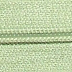 May include: A close-up of a light green zipper tape with a white zipper pull. The zipper tape has a textured surface.