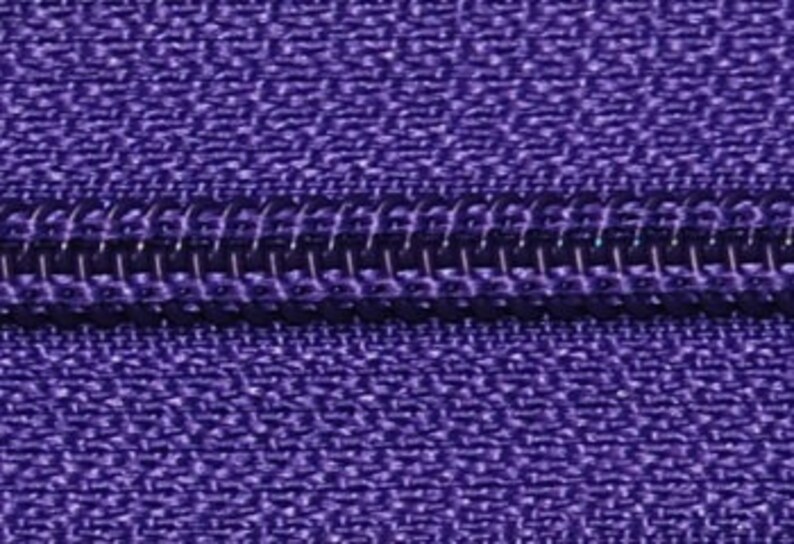 May include: Close-up of a purple zipper with a black zipper pull.