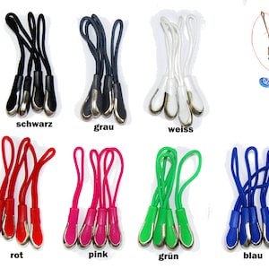 Könnte beinhalten: Sortiment an Reißverschluss-Zierbändern in verschiedenen Farben, darunter Schwarz, Grau, Weiß, Rot, Pink, Grün und Blau. Jeder Zipper hat eine silberne Metallspitze und eine Schlaufe zum Anbringen an einem Reißverschluss.