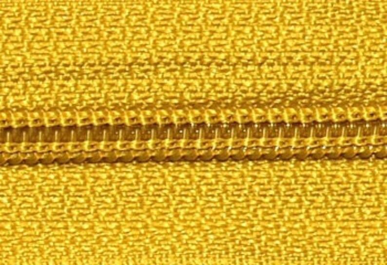 May include: Close-up of a gold zipper with a yellow fabric tape.
