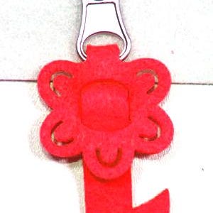 Könnte beinhalten: Ein roter Reißverschlussanhänger aus Filz mit einem Blumendesign und einem blattförmigen Akzent. Der Reißverschlussanhänger ist an einem silbernen Metallreißverschluss befestigt. Für Kleidung oder Accessoires.