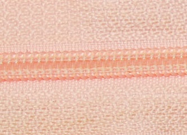 May include: Close-up of a pink zipper with a white zipper tape.