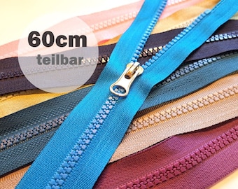 May include: A close-up of a variety of zipper tapes, including a blue zipper tape with a gold slider. The text "60cm teilbar" is visible in the image.