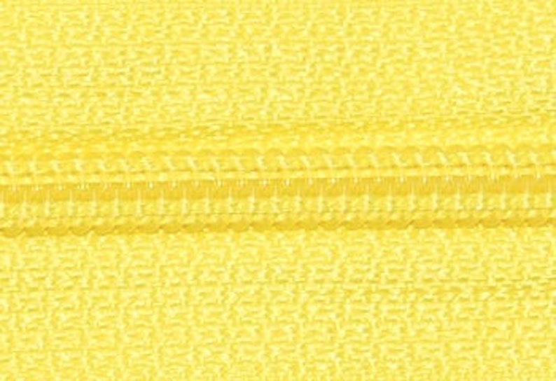 May include: Close-up of a yellow zipper with a smooth, textured surface.