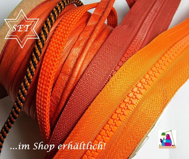 May include: A collection of various orange and reddish-orange zippers and cords wound on spools. The assortment includes textured orange cords, a black and orange patterned cord, and several smooth orange and red zipper tapes with plastic teeth.