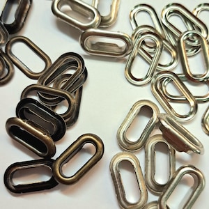 Könnte beinhalten: Nahaufnahme von zwei Stapeln ovaler Metallstifte. Ein Stapel ist silberfarben und der andere bronzefarben.