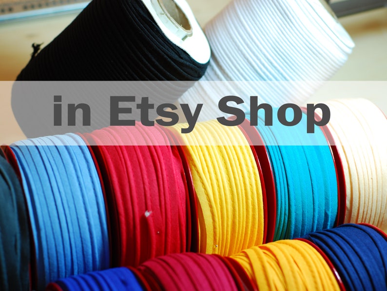 May include: Multiple spools of colorful fabric cord arranged in rows. The collection includes black, white, light blue, red, yellow, turquoise, and dark blue spools. The text "in Etsy Shop" is overlaid across the center of the image.