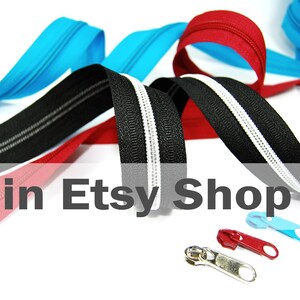 May include: A collection of nylon coil zippers in black, red, and bright blue, featuring a central white stripe on the black zipper tape. Three separate metal zipper pulls in silver, red, and blue are positioned in the foreground of the image.