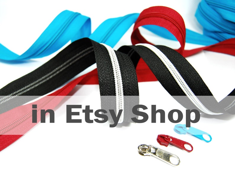 May include: A collection of nylon coil zippers in black, red, and bright blue, featuring a central white stripe on the black zipper tape. Three separate metal zipper pulls in silver, red, and blue are positioned in the foreground of the image.