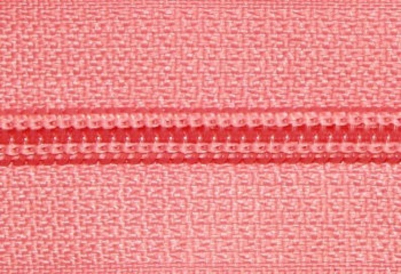 May include: Close-up of a pink zipper with a red zipper pull.