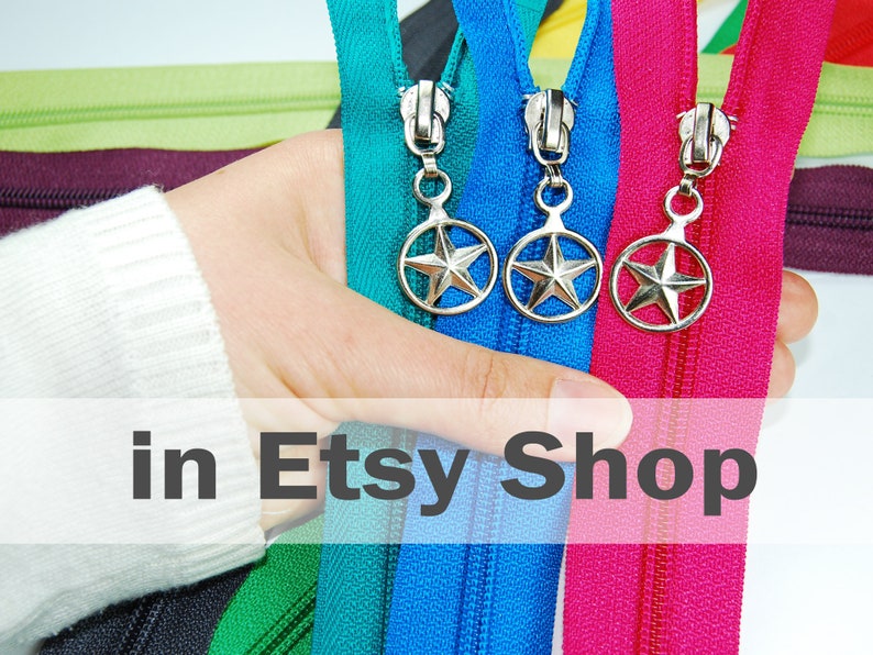 May include: A collection of colorful fabric zippers featuring silver-toned metal pulls with a star-shaped design enclosed in a circular frame. The zippers are displayed in various vibrant shades including teal, blue, magenta, green, and dark purple.