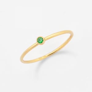 Puede incluir: Un delicado anillo de oro con una pequeña piedra preciosa verde redonda.