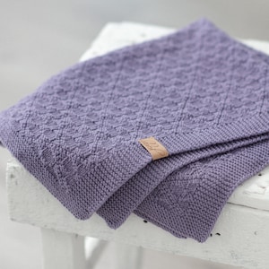 Può includere: Una morbida copertina per neonati in maglia di colore lilla con un piccolo cartellino in pelle che dice "Little Giraffe".