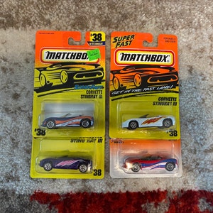 May include: Four Matchbox die-cast toy cars on their original packaging. The cars are all Corvette Stingray models, with different color schemes and designs. The packaging features the Matchbox logo and the words "Super Fast" and "Get in the Fast Lane!"