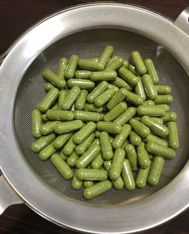 Puede incluir: Un colador de metal lleno de c&aacute;psulas verdes. Las c&aacute;psulas est&aacute;n llenas de un polvo verde.