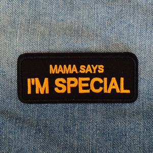 Könnte beinhalten: Schwarzer und gelber gestickter Aufnäher mit dem Text "Mama Says I'm Special" auf einem blauen Jeansstoff.