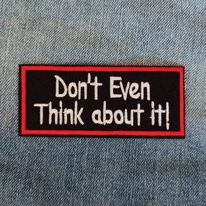 Könnte beinhalten: Schwarzer und roter gestickter Aufnäher mit weißem Text, der "Don't Even Think about it!" lautet.
