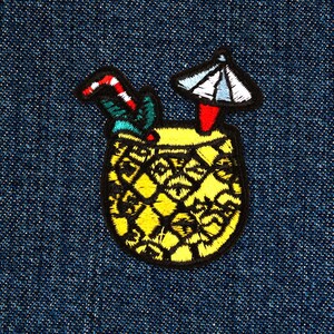 May include: Embroidered iron-on patch of a yellow pineapple with a red and white striped straw and a white paper umbrella. The pineapple is on a blue denim background.
