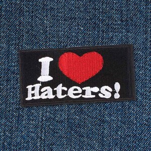 May include: Black and red embroidered patch with the text "I love haters!" in white lettering. The patch features a red heart with a white outline.