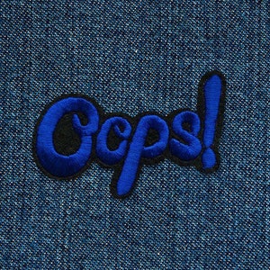 May include: Blue embroidered patch with the word "Oops!" on a denim background.