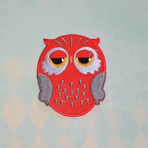 Puede incluir: Parche de búho rojo bordado con alas grises y ojos amarillos.