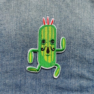 Op de afbeelding: Groen cactus-personage met een rode mohawk, zwarte ogen en een zwarte snor. De cactus draagt een witte omtrek en rent.