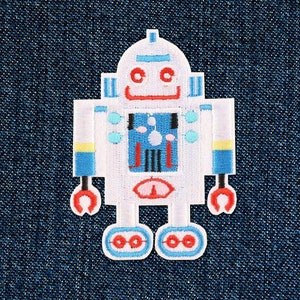 Könnte beinhalten: Weißer Roboter-Patch mit blauen und gelben Akzenten. Der Roboter hat ein lächelndes Gesicht, einen runden Körper und zwei Arme mit roten Händen. Der Roboter hat zwei Beine mit blauen und roten Rädern.