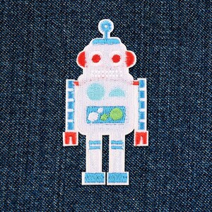 Op de afbeelding: Witte robotpatch met blauwe en groene details. De robot heeft rode ogen en een blauwe antenne. De patch is op een blauwe denim achtergrond.