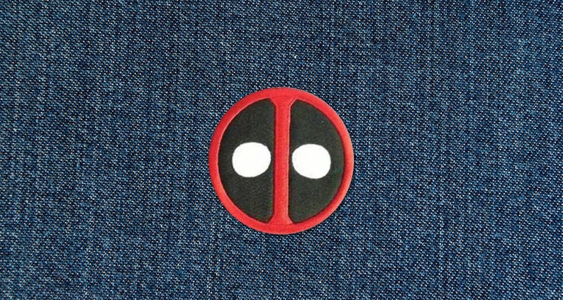 Op de afbeelding: Rode en zwarte cirkel met twee witte cirkels erin, die lijken op het maskersontwerp van het personage Deadpool.