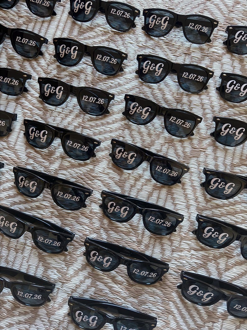 May include: Black sunglasses with the text "G&G" and the date "12.07.26" printed on the lenses. The sunglasses are arranged in a repeating pattern on a textured surface.
