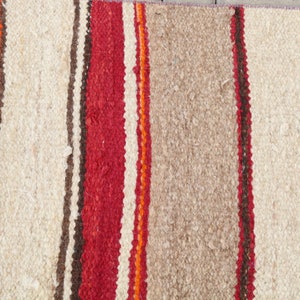 May include: A striped rug with alternating bands of white, red, orange, and brown. The rug is woven with a textured, fuzzy surface.