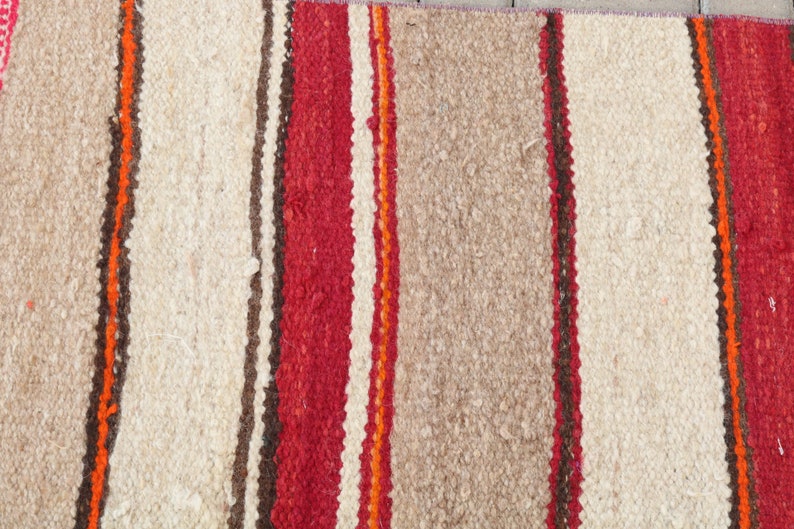 May include: A striped rug with alternating bands of white, red, orange, and brown. The rug is woven with a textured, fuzzy surface.
