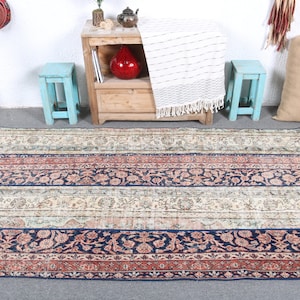 May include: A vintage patterned rug with a blue, red, and cream color scheme. The rug has a striped design with floral motifs.