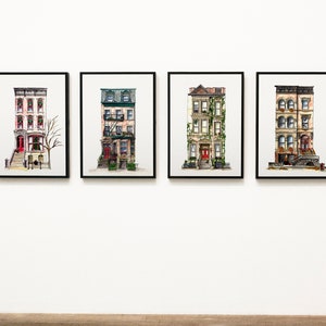 May include: Four framed watercolor paintings of brownstone buildings with red doors and green ivy. The buildings are depicted in a realistic style with details like windows, fire escapes, and stoops.