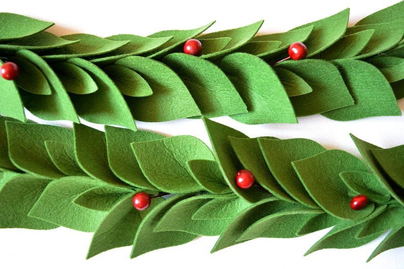May include: A green felt garland with red felt berries. The garland is made of individual leaves that are sewn together.