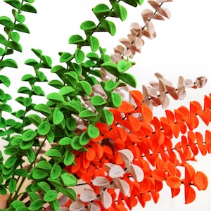 May include: A bunch of artificial eucalyptus stems in green, orange, and beige colors. The stems are made of felt and have a soft, fuzzy texture.