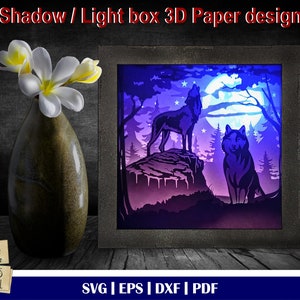 May include: A 3D papercraft design of two wolves howling at the moon in a forest setting. The design is illuminated with blue and purple lights, creating a shadow box effect. The design is available as a digital download in SVG, EPS, DXF, and PDF formats.