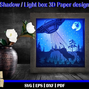 May include: A 3D papercraft design of a UFO flying over a forest at night. The design is in a shadow box frame with a blue background and stars. The design is ready to be cut and assembled.