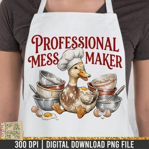 Puede incluir: Delantal blanco con una ilustración de un pato con gorro de chef, rodeado de cuencos, huevos y batidores. El texto "PROFESSIONAL MESS MAKER" está en escritura roja. Descarga digital.