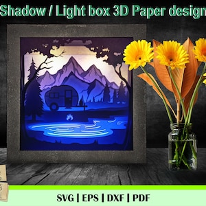 Könnte beinhalten: Ein 3D-Papiermodell eines Wohnmobils, das an einem See in einer Berglandschaft geparkt ist. Das Design ist für die Verwendung mit einer Lichtbox gedacht, um einen Schatteneffekt zu erzeugen. Das Design ist in den Formaten SVG, EPS, DXF und PDF verfügbar.