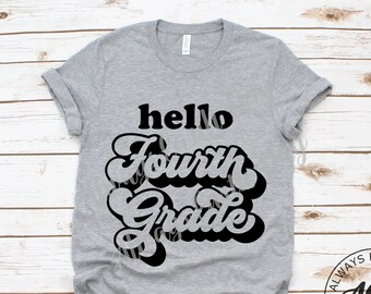May include: A gray t-shirt with the text "hello Fourth Grade" in black retro-style lettering. The text is centered on the shirt. The shirt is on a white wooden background.